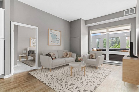 A living room with a grey couch, a white rug, and a painting on the wall.