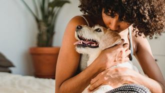 a woman kissing a dog on a bed