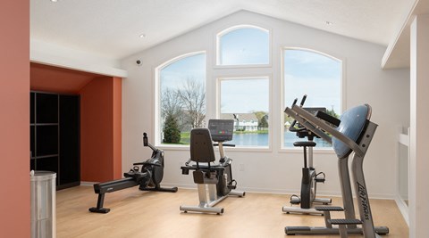 three exercise machines in a room with three large windows