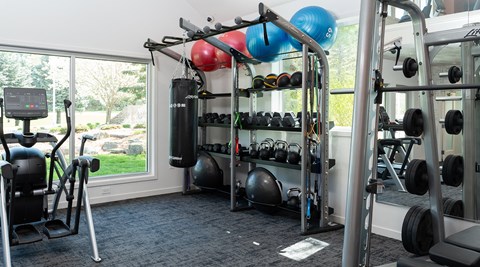 a gym with weights and cardio equipment and a window