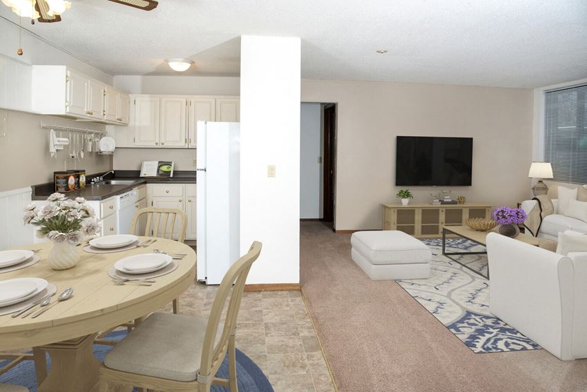 a living room with a table and chairs and a kitchen in the background