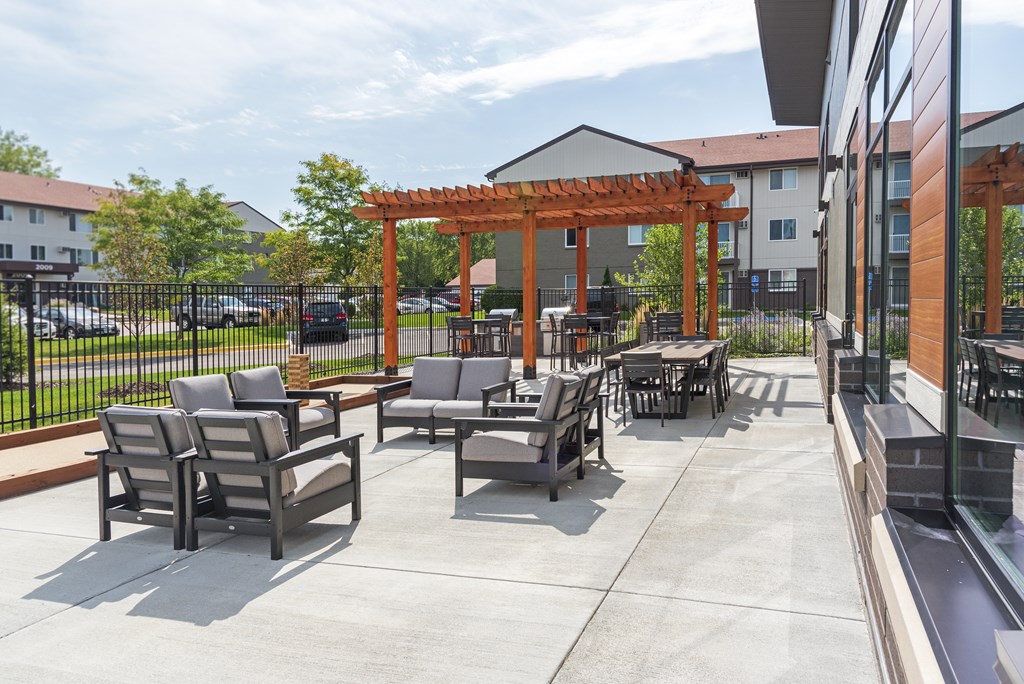A patio with chairs and a pergola.