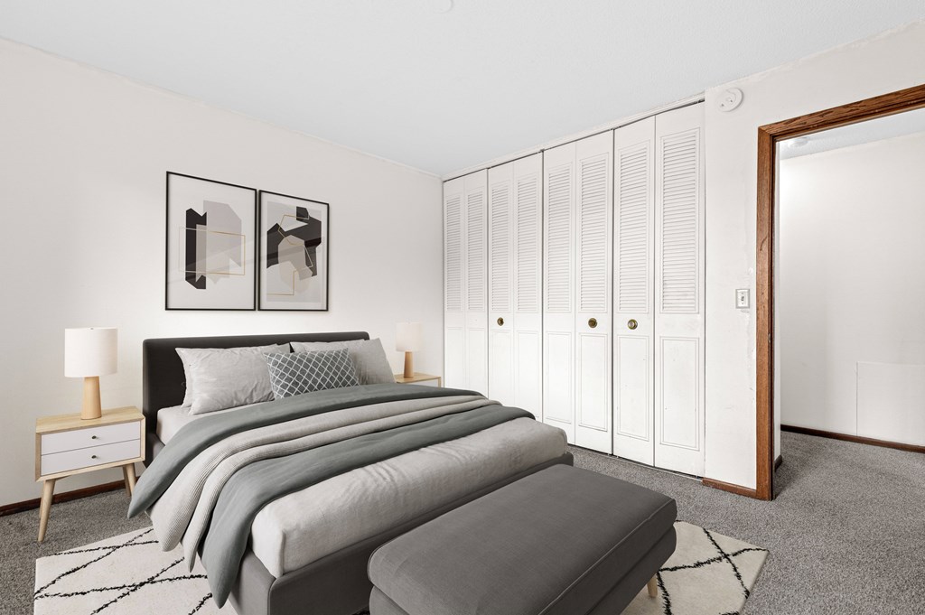 A bedroom with a bed, nightstand, and wardrobe.