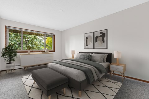A bedroom with a large bed and a window overlooking a green tree.