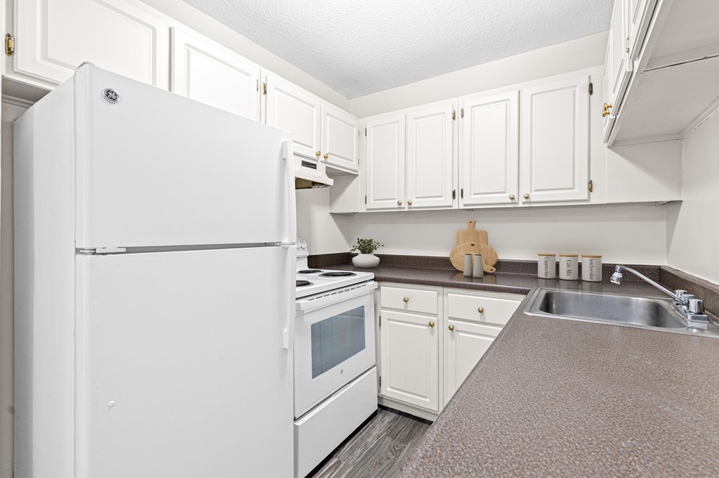 A white refrigerator is in a kitchen with white cabinets.