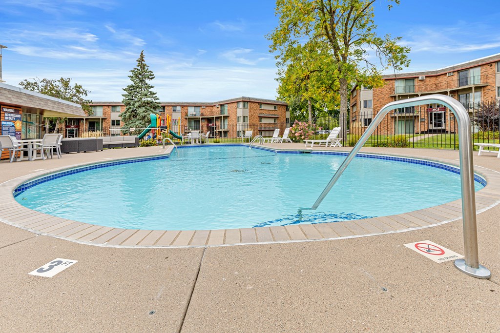 A swimming pool surrounded by a metal railing and a no swimming sign.