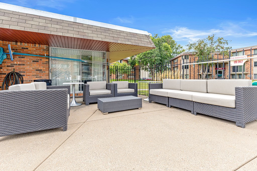 A patio with grey furniture and a brick building in the background.