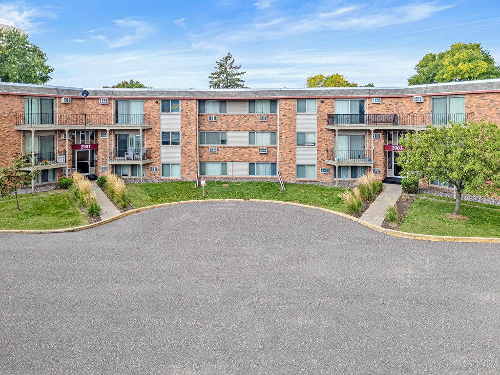A large apartment complex with a parking lot in front.