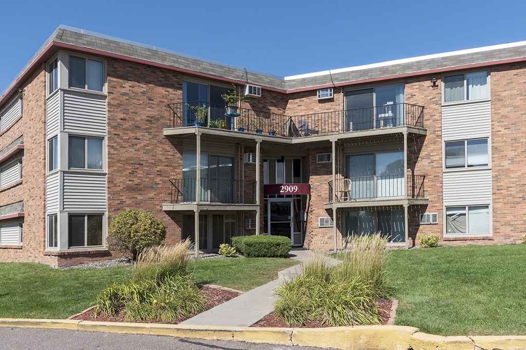 a brick apartment building with balconies and a sidewalk