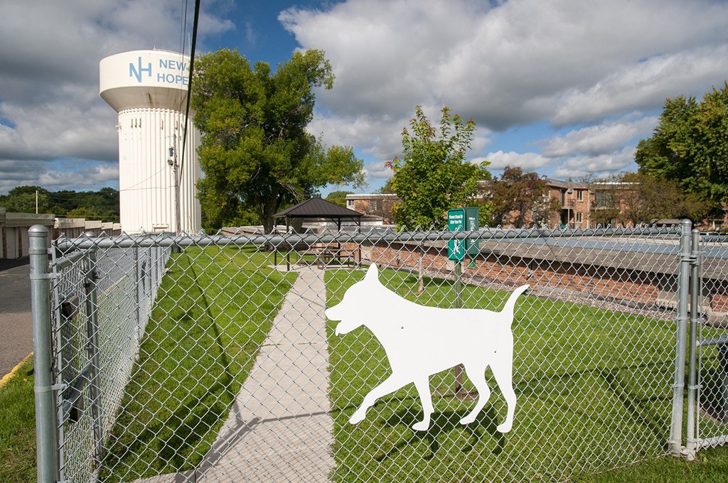 a white dog on a fence in front of a water tower