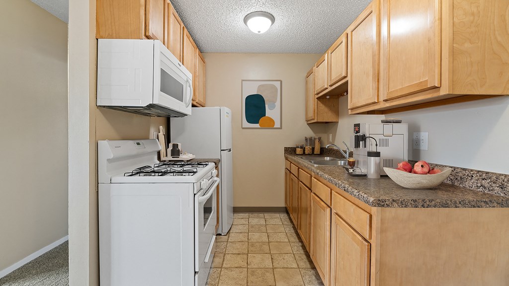 our apartments have a kitchen with white appliances and wood cabinets