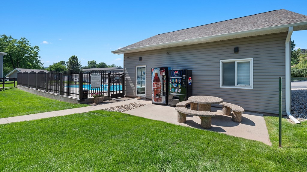 a picnic table in front of a house with a gas station