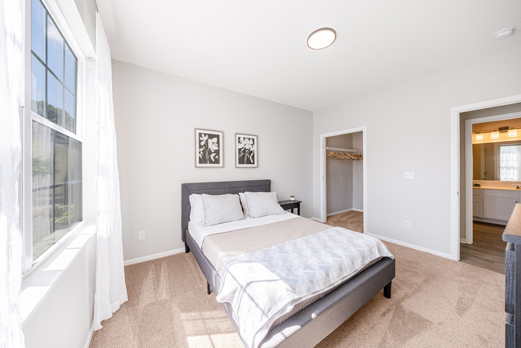 A bedroom with a large bed and a window with curtains.