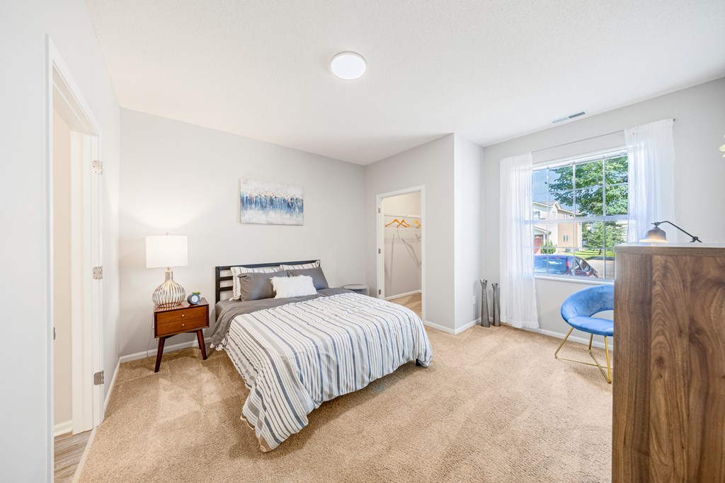 A bedroom with a bed, nightstand, and chair.