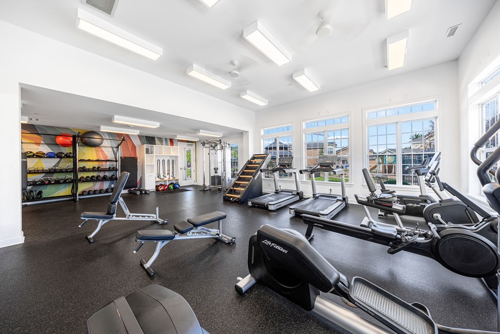 A gym with a variety of equipment including treadmills, weights, and exercise machines.
