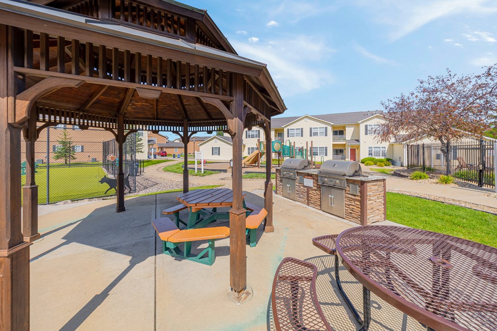 A patio with a table and chairs under a wooden pergola.