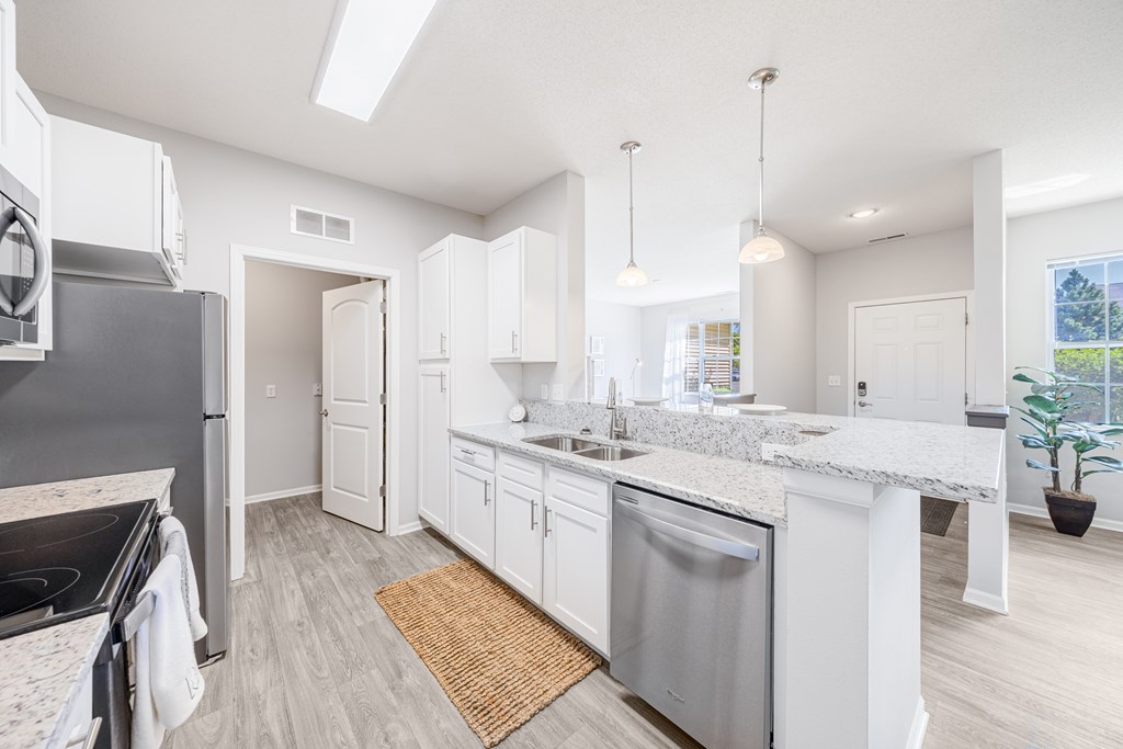 A modern kitchen with a stainless steel dishwasher and white cabinets.