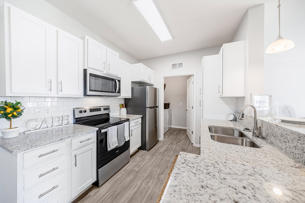 A kitchen with white cabinets and a granite countertop.