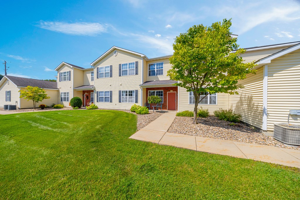 A large house with a red door and a tree in front.