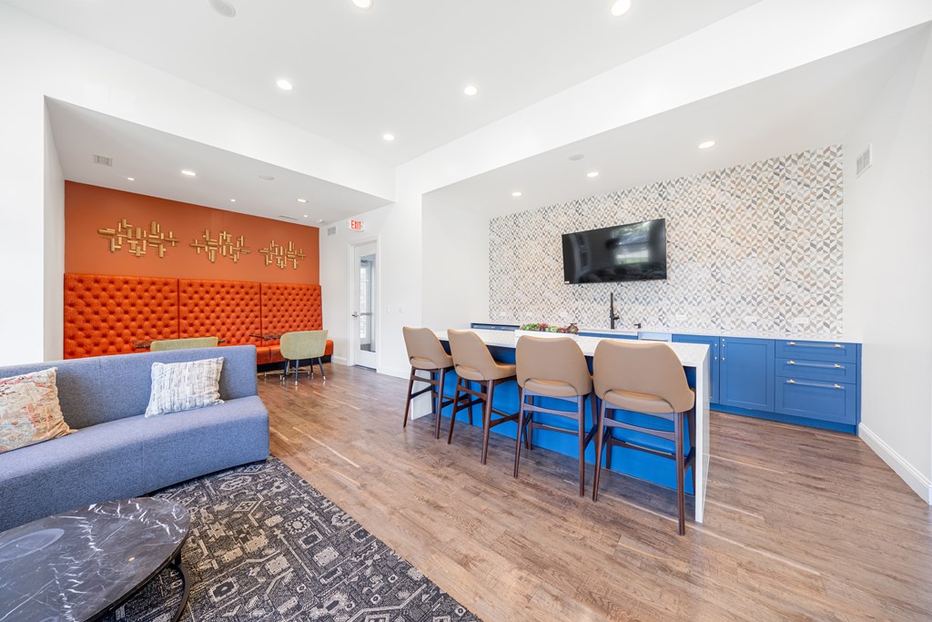 A living room with a grey couch and a blue kitchen area.