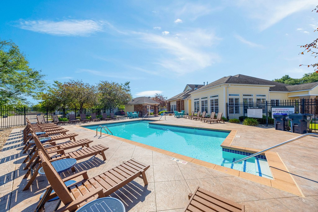 A sunny day at the pool with lounge chairs and a clear blue sky.