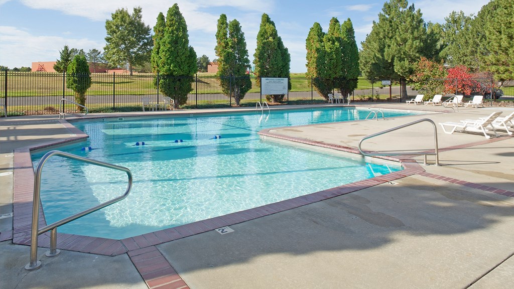 a swimming pool with chairs and a fence around it