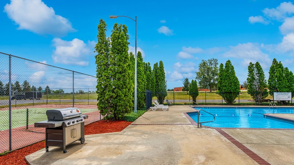 a grill next to a swimming pool with a chain link fence