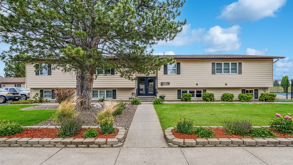 a beige house with a tree and a sidewalk in front of it