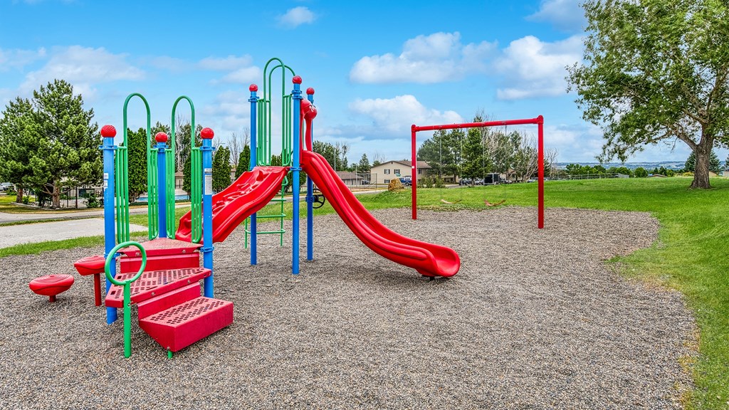 a playground with a red slide and monkey bars in a park