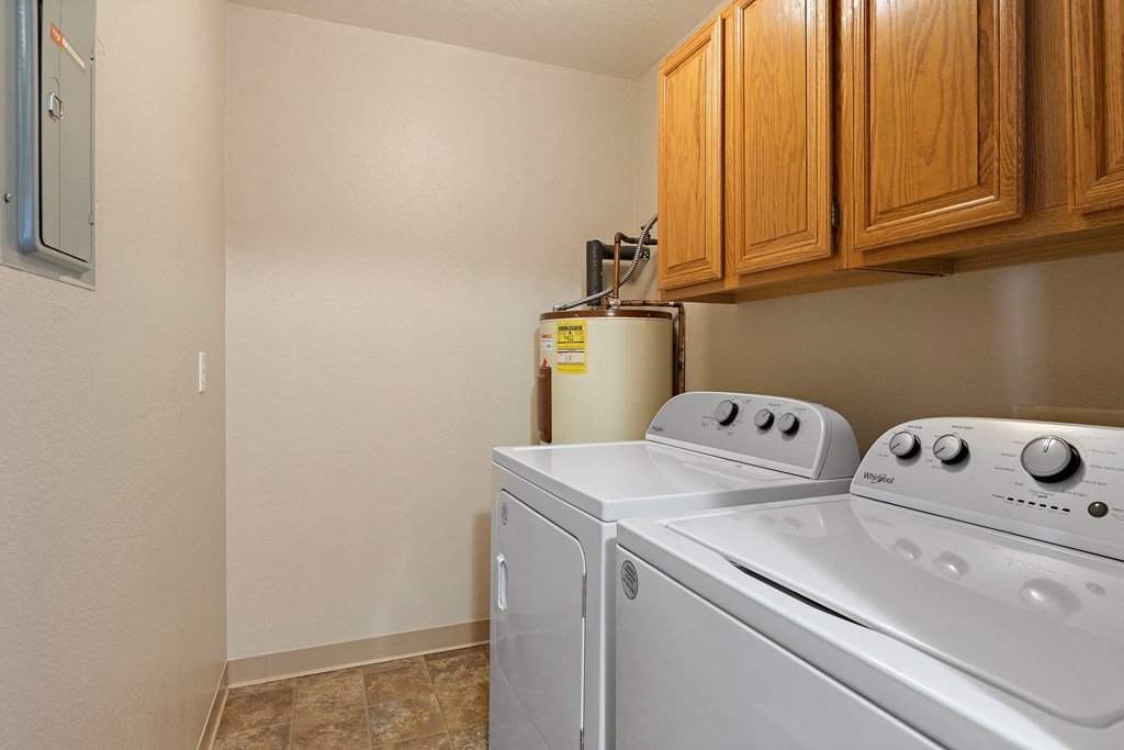 the laundry room has a washer and dryer and wood cabinets
