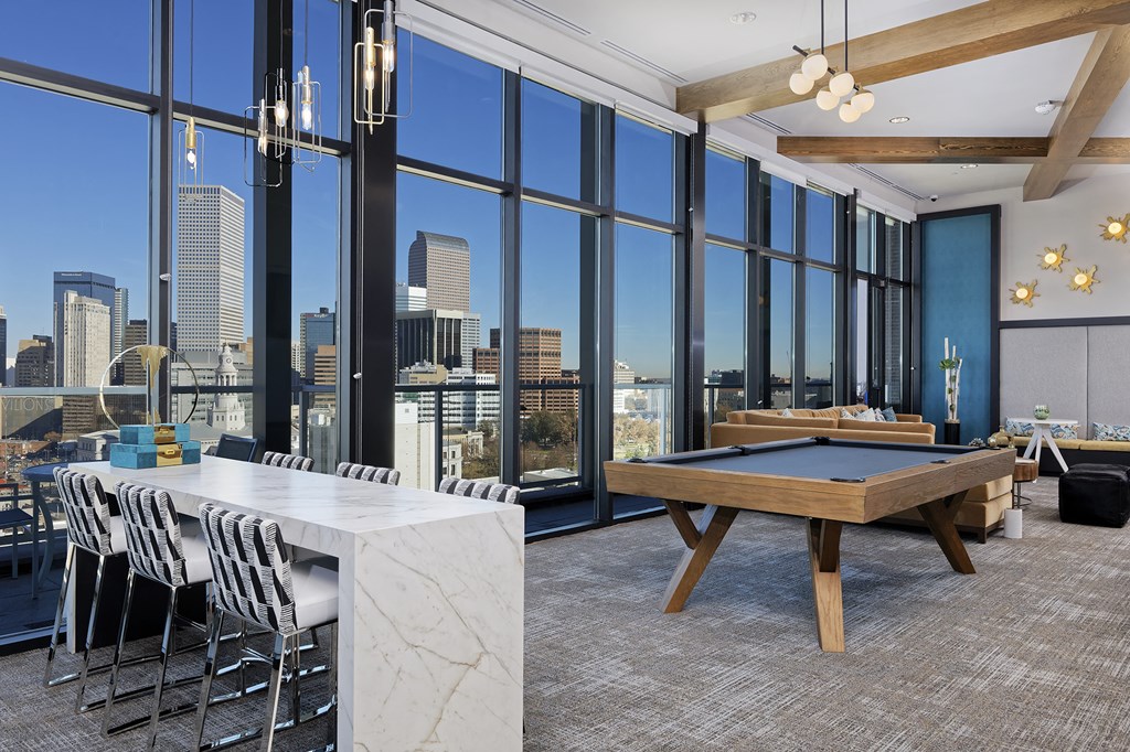 Sky lounge with granite table, pool table and large glass windows with view of Denver skyline