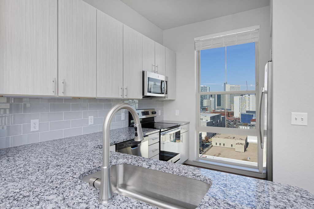 Kitchen with white cabinets, stainless steel appliances and granite countertops, window with skyline view
