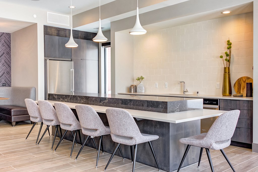 a kitchen with a long counter and chairs in front of it