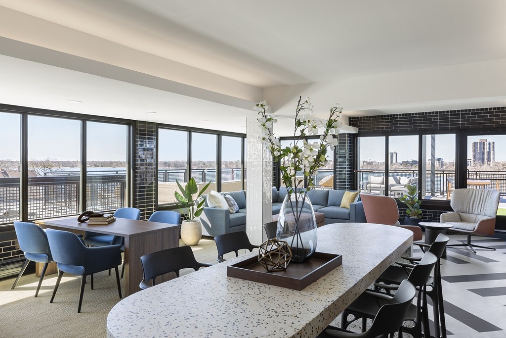 a living room with a table and chairs and large windows