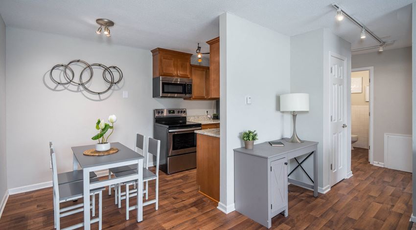a dining area with a table and chairs and a kitchen in the background