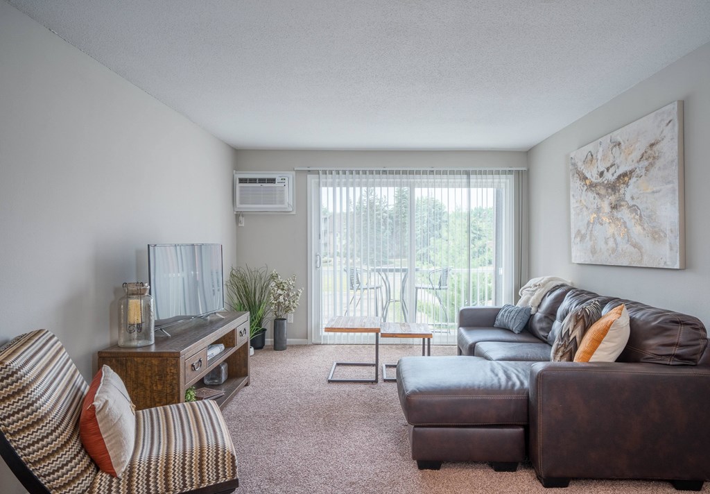 A living room with a brown couch, a striped chair, and a painting on the wall.