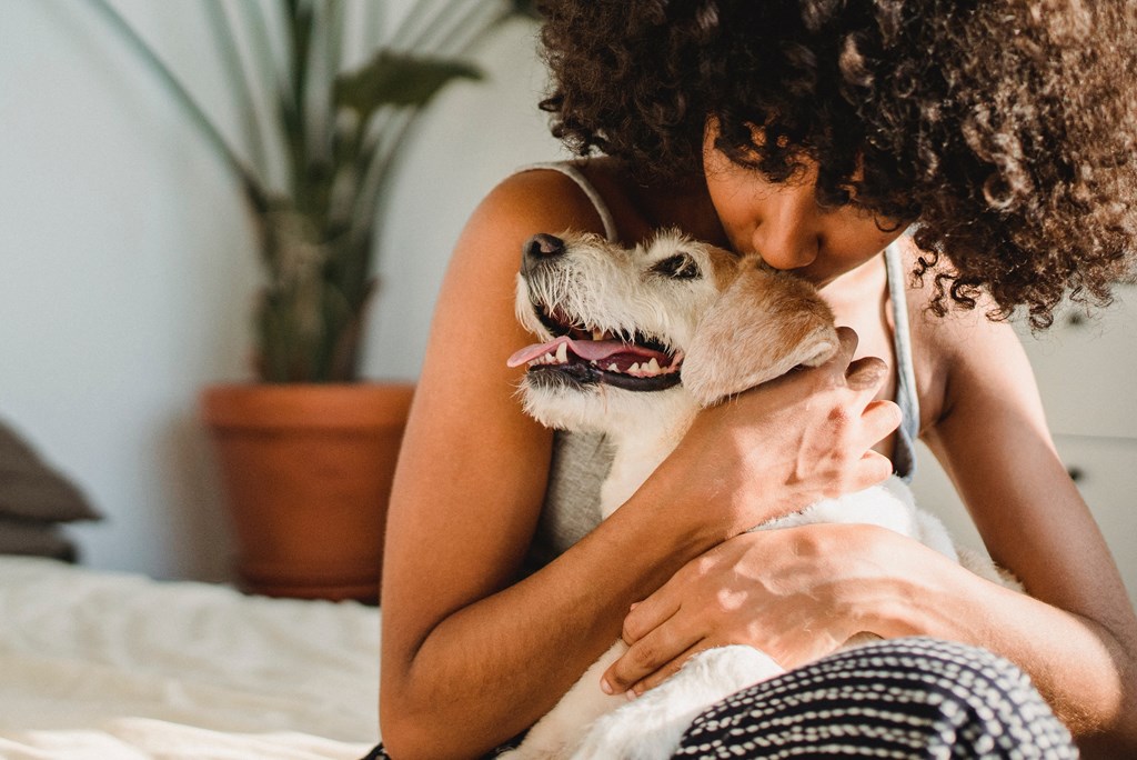 a woman hugging her dog on a bed