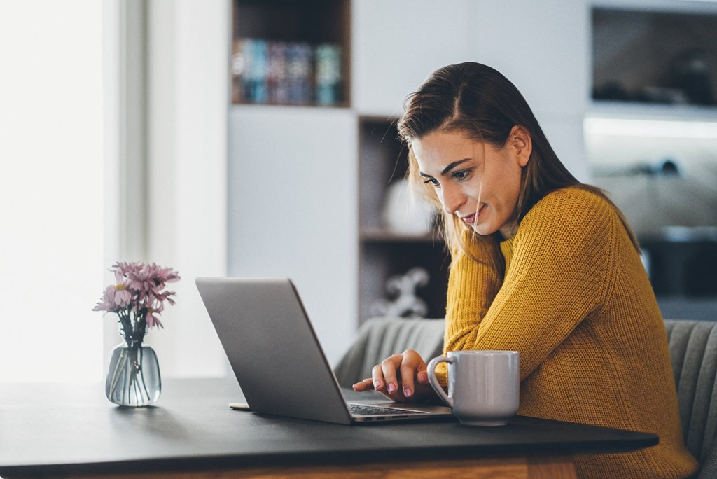 a woman sitting at a table with a laptop and a cup of coffee