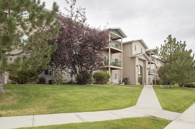 Building exterior of Country Meadows with lush green grass and sidewalks leading up to the building entrance.