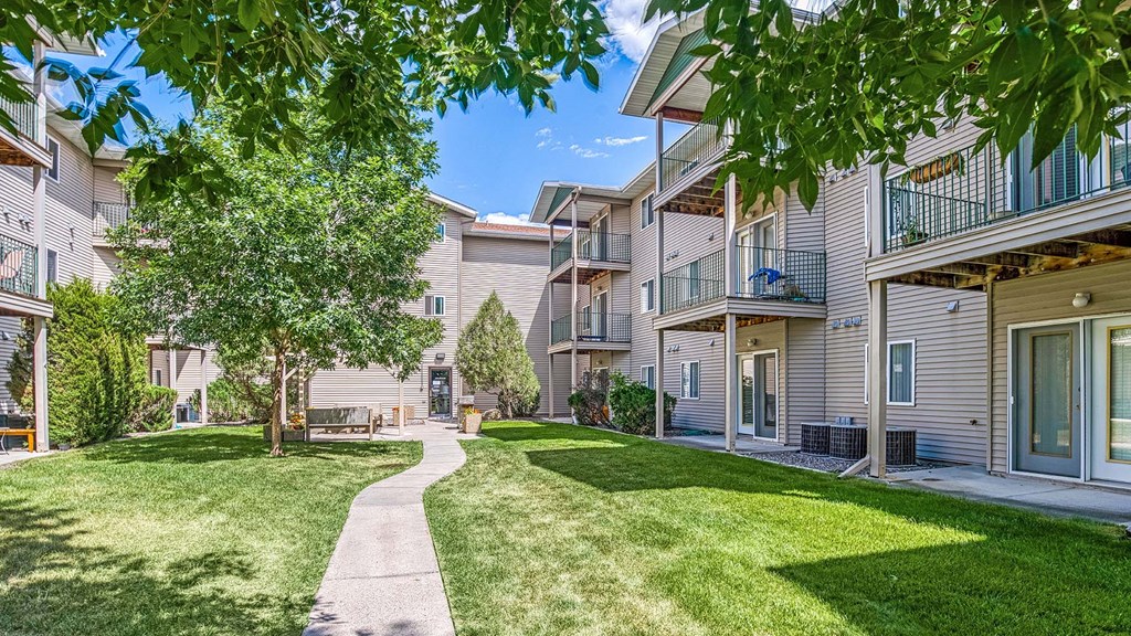 a walkway between two apartment buildings with grass and trees