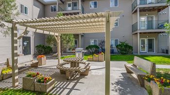 a patio with a picnic table and a pergola in front of a building