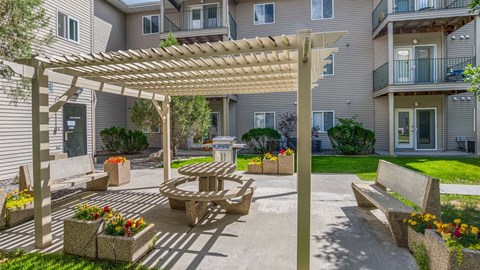 a patio with a picnic table and a pergola in front of a building