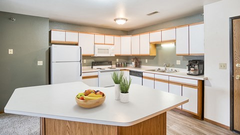 a kitchen with white cabinets and a bowl of fruit