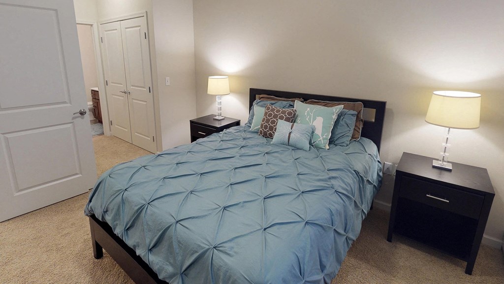 a bedroom with a bed and two night stands and a closet