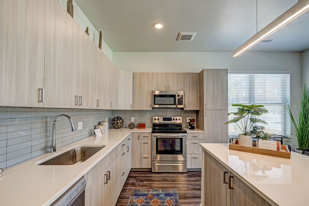 A modern kitchen with cabinets, white countertops and kitchen island.