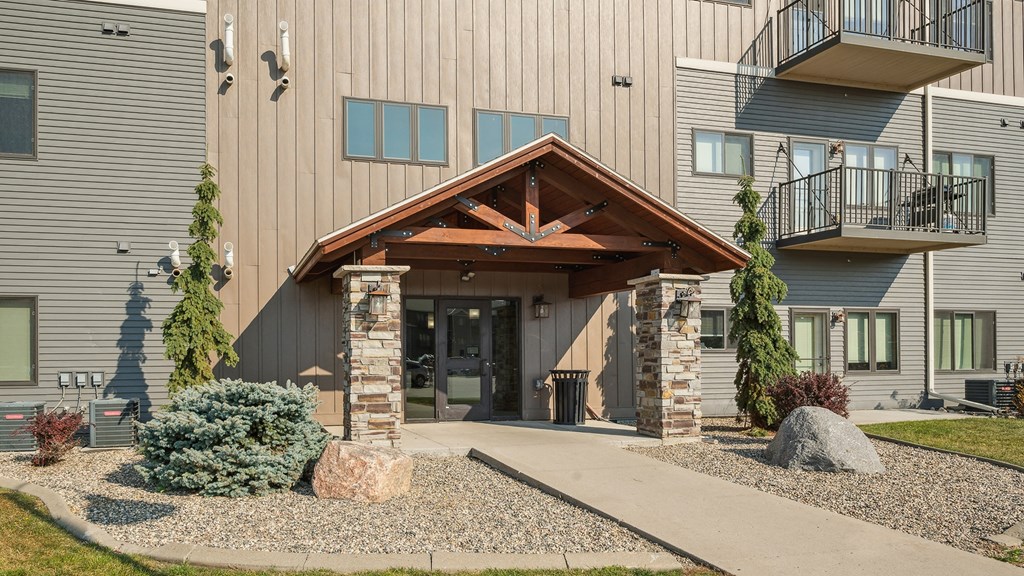A modern building with a wooden front entrance and a gravel path leading to it.