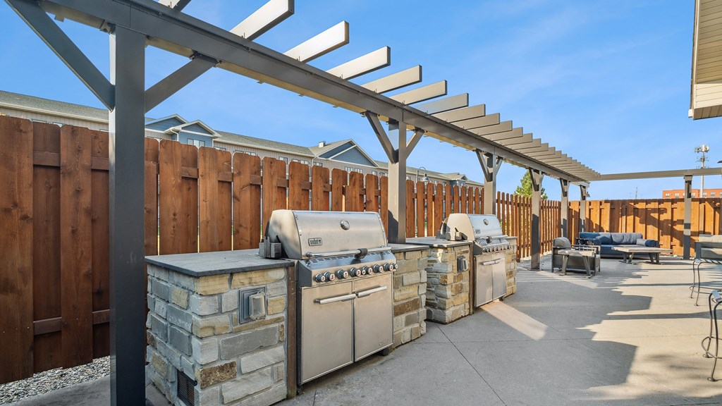 A patio with a BBQ and a pergola.