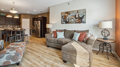 A living room with a grey couch and a painting on the wall.