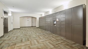 A long hallway with a carpeted floor and a wall of lockers on the right.