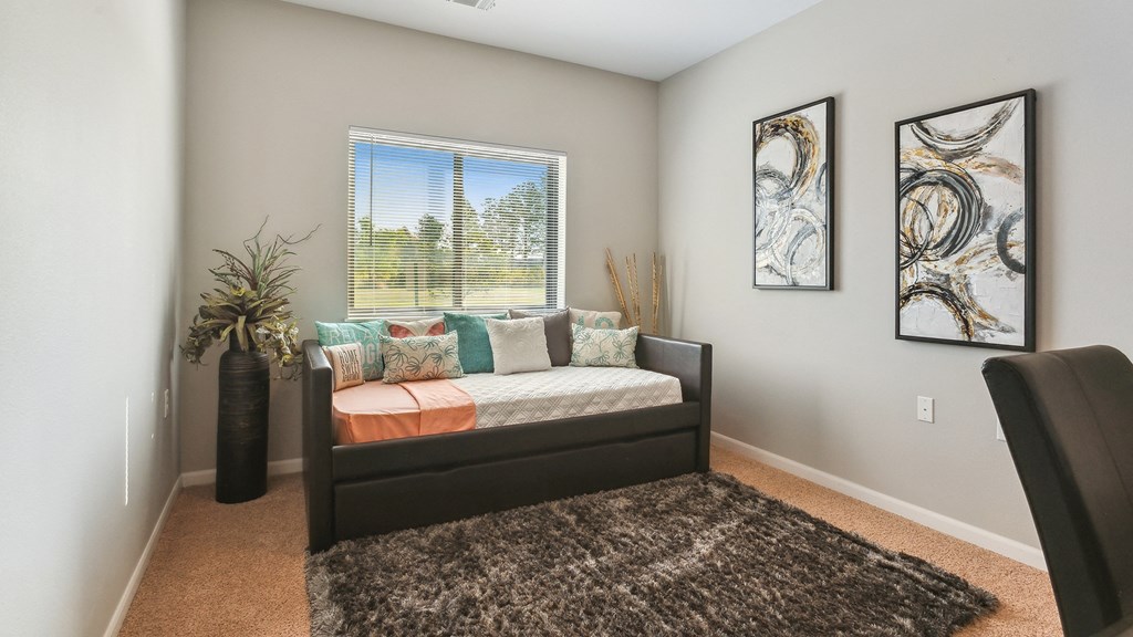 A bedroom with a bed, pillows, a carpet, and two pieces of artwork on the wall.